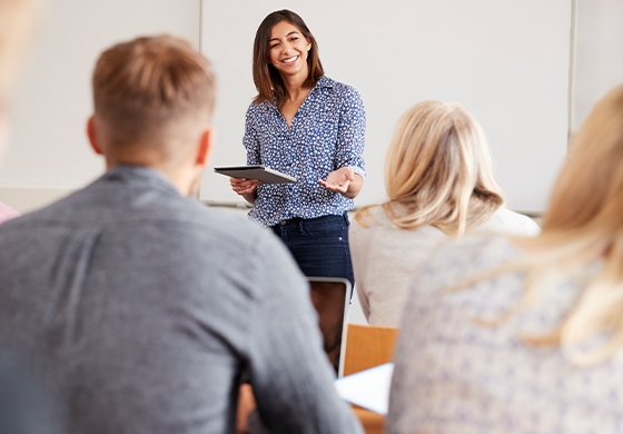 Smiling business woman giving training on business and economics to a mixed UK crowd